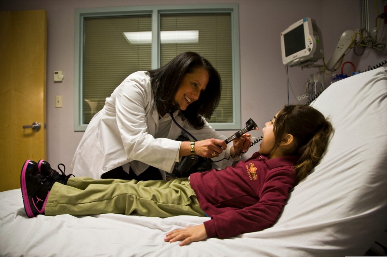 A doctor tending to a young girl in the hospital.