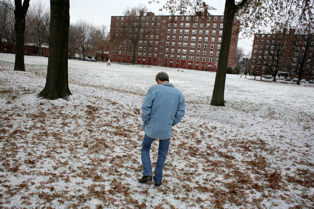 A man walks over a snow covered lawn.
