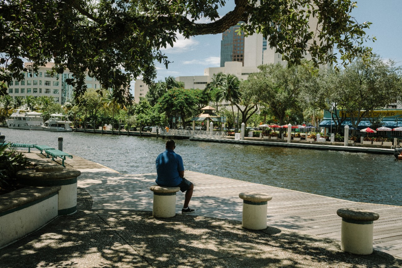 A man sits alone by a waterfront park.