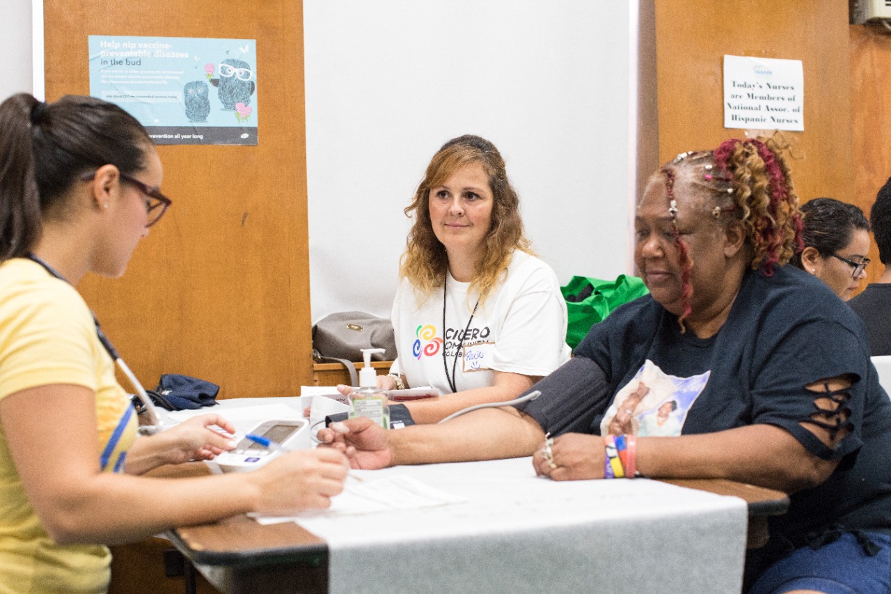 Three women talking at a table at a health fair.