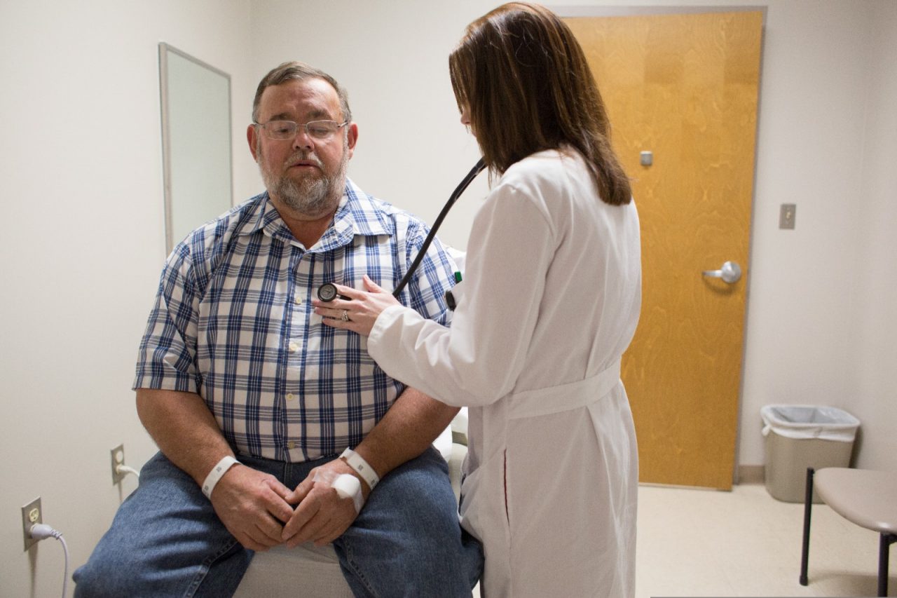 A doctor listens to a patient's heart with a stethoscope.