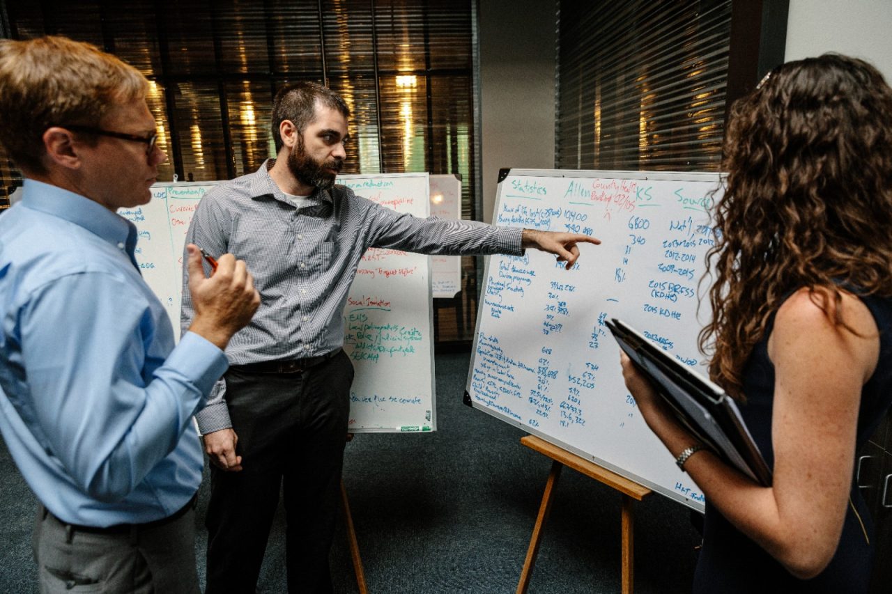 Professionals review information on a white board. 